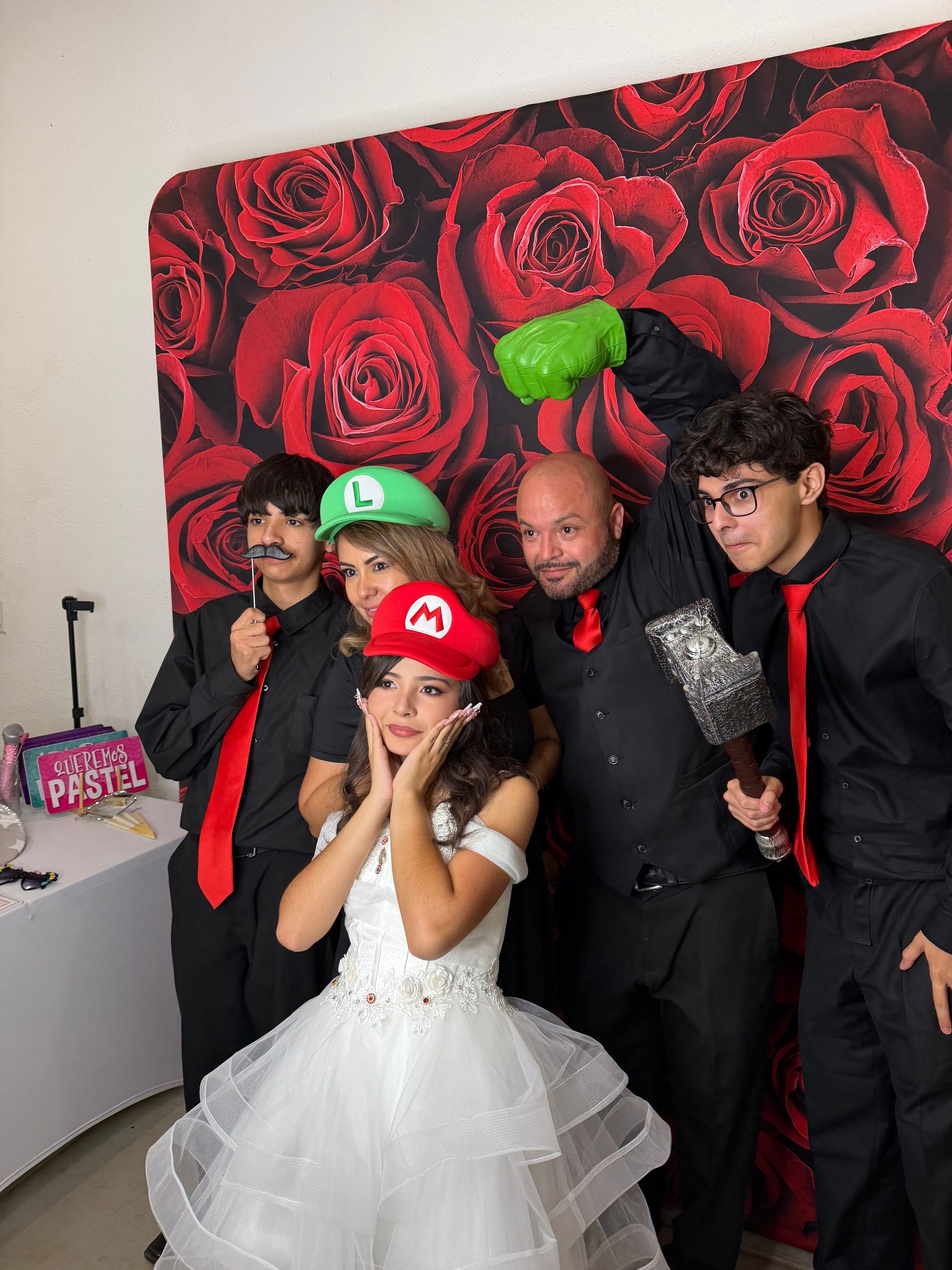 Ivana posing with her family wearing fun Mario-themed props at her Quinceañera photo booth in Perris, CA.