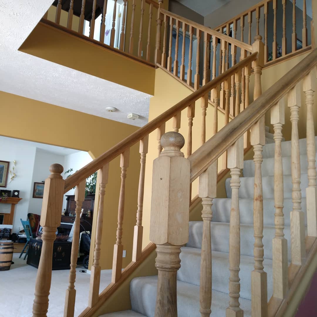Staircase with wooden railing and white carpeted steps leading to an upper level, yellow walls.