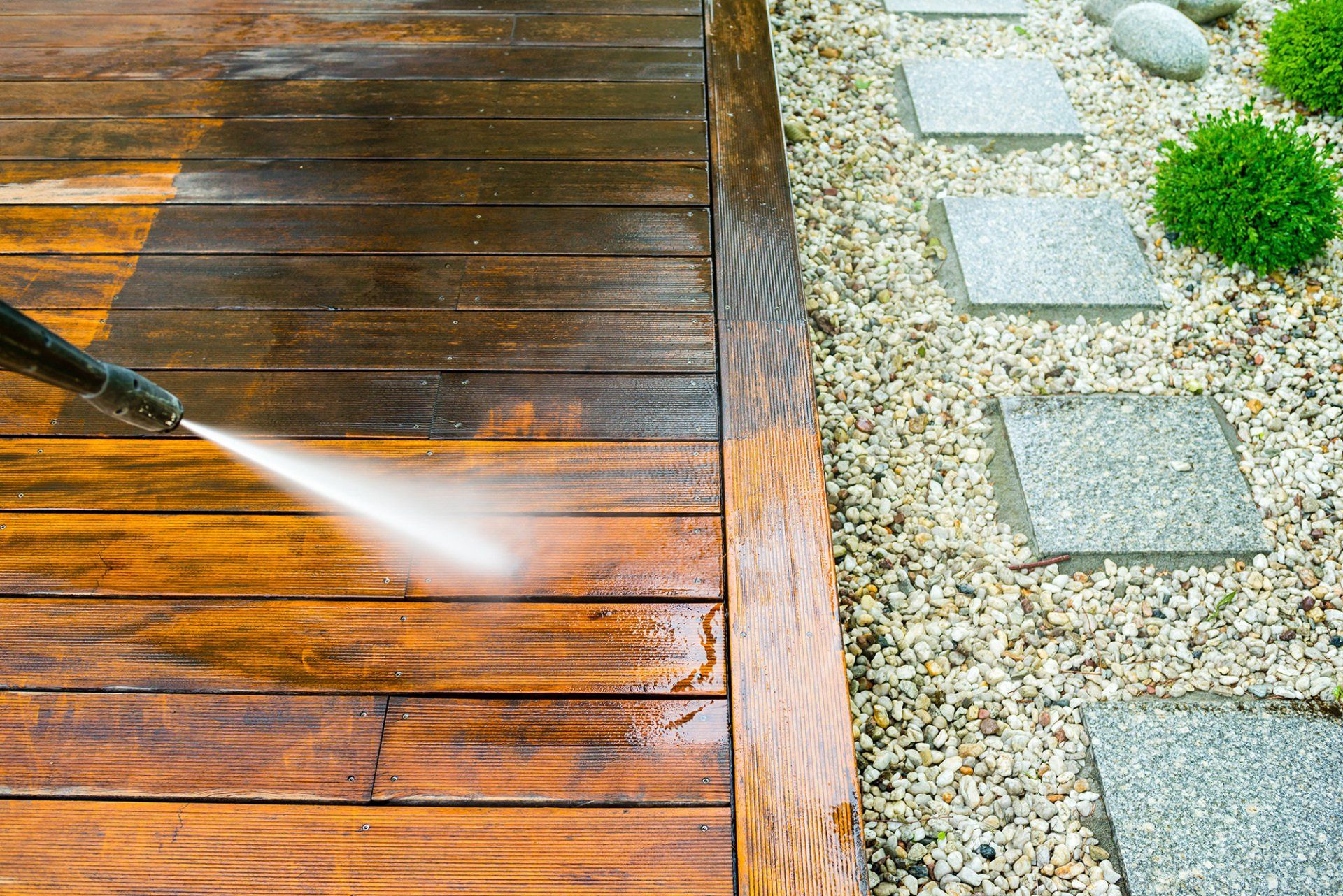 Pressure washing a wooden deck, showing the clean versus dirty sides.
