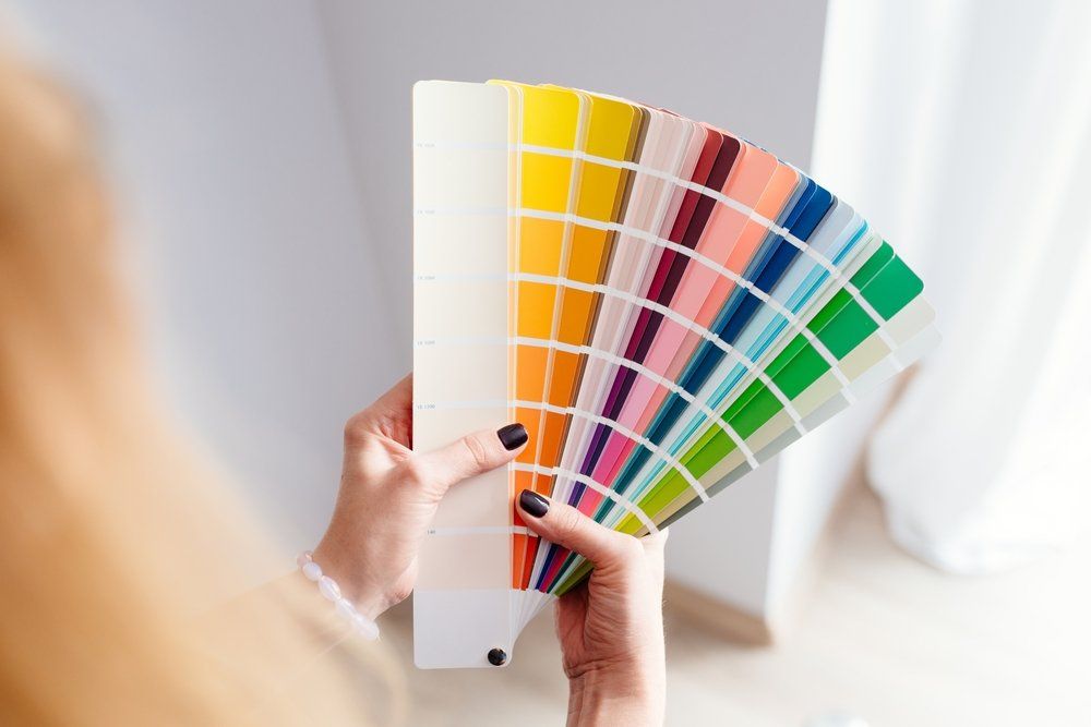 Person holding a color palette, choosing paint colors for a room.