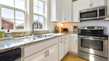 Bright kitchen with white cabinets, stainless steel appliances, and granite countertops.