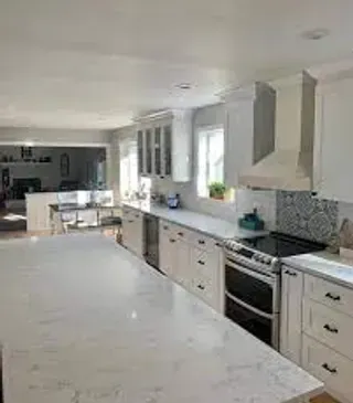 White kitchen with large island, stainless steel appliances, and overhead cabinets.