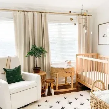 A nursery with light wood crib and bassinet. Cream curtains and a white rocking chair.