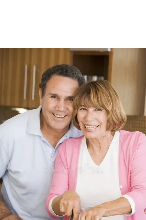 An older couple outdoors smiling; man in orange sweater, woman in purple holding a cup.