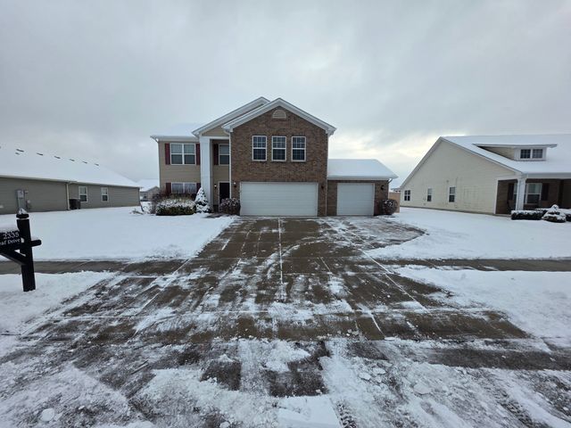 Snow-covered suburban house with cleared driveway on a cloudy winter day