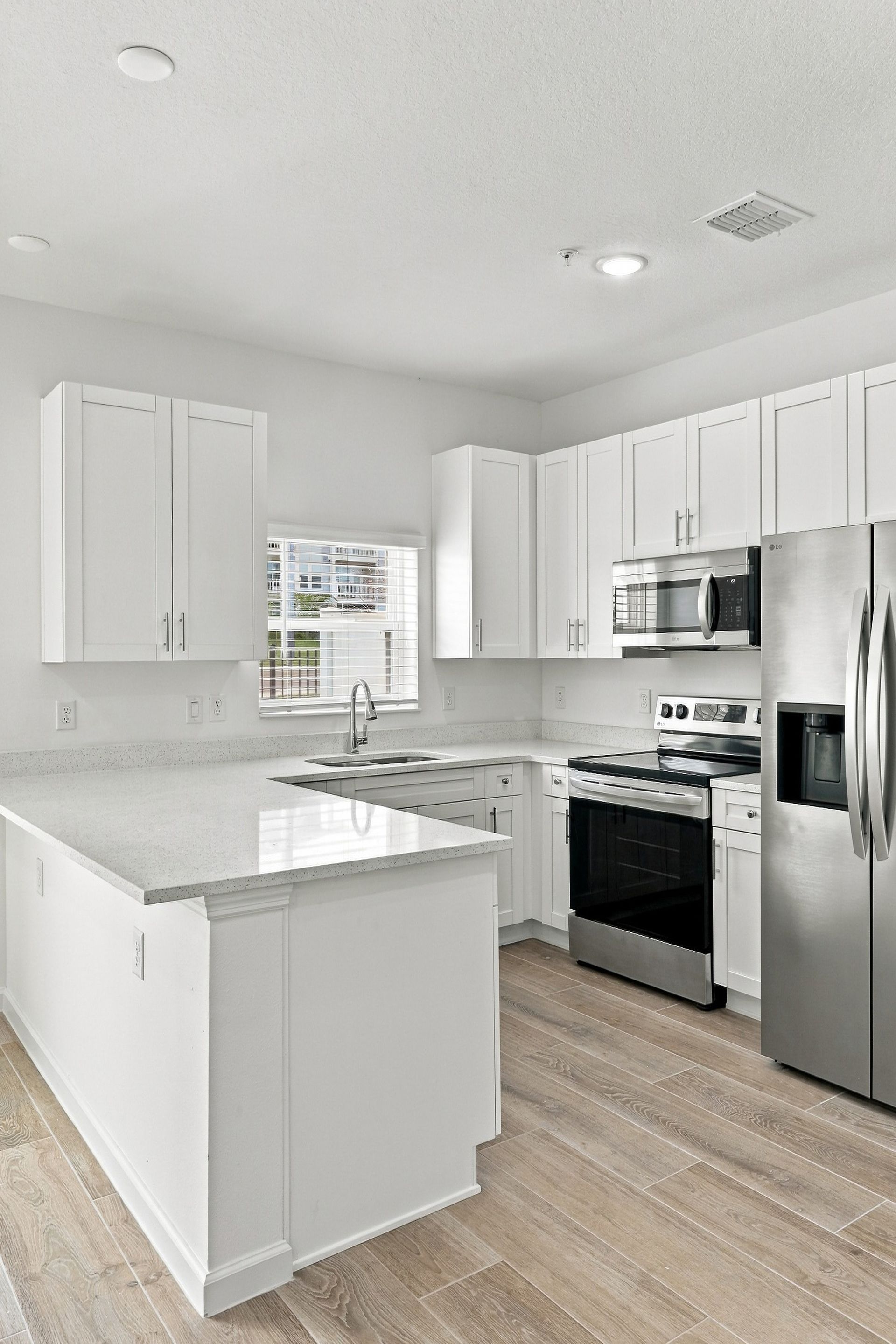 Bright white modern kitchen with island, stainless appliances, and light wood flooring