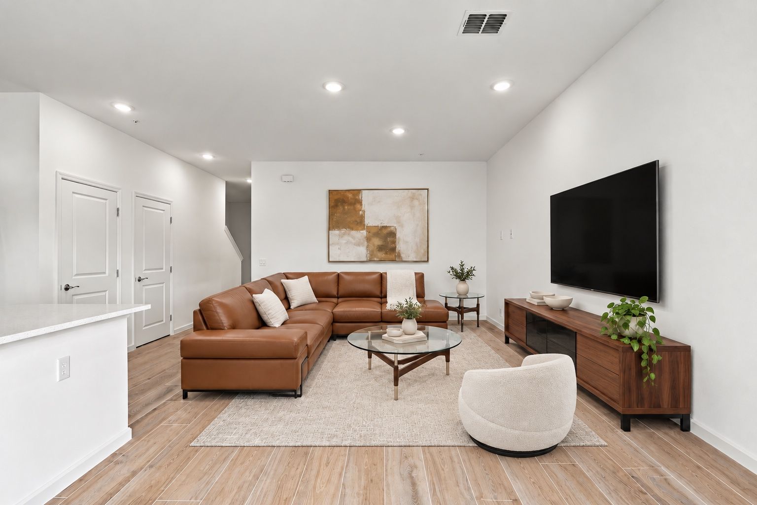 Modern living room with brown sectional, wall-mounted TV, wooden console, and neutral decor