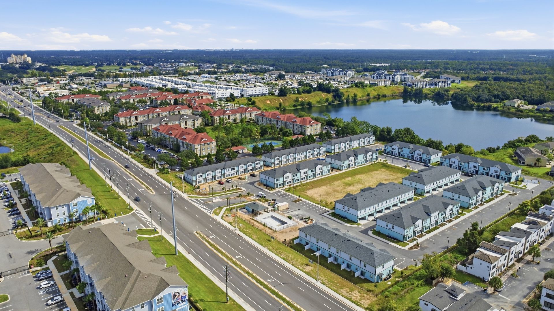 Aerial view of a suburban neighborhood with roads, houses, and a large lake in the background.