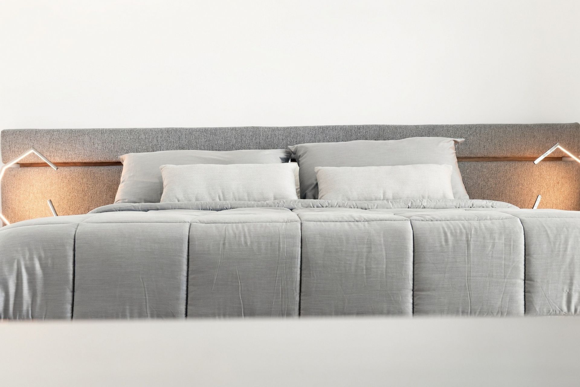 Modern bedroom with a gray upholstered bed, white bedding, and warm bedside lamps on both sides