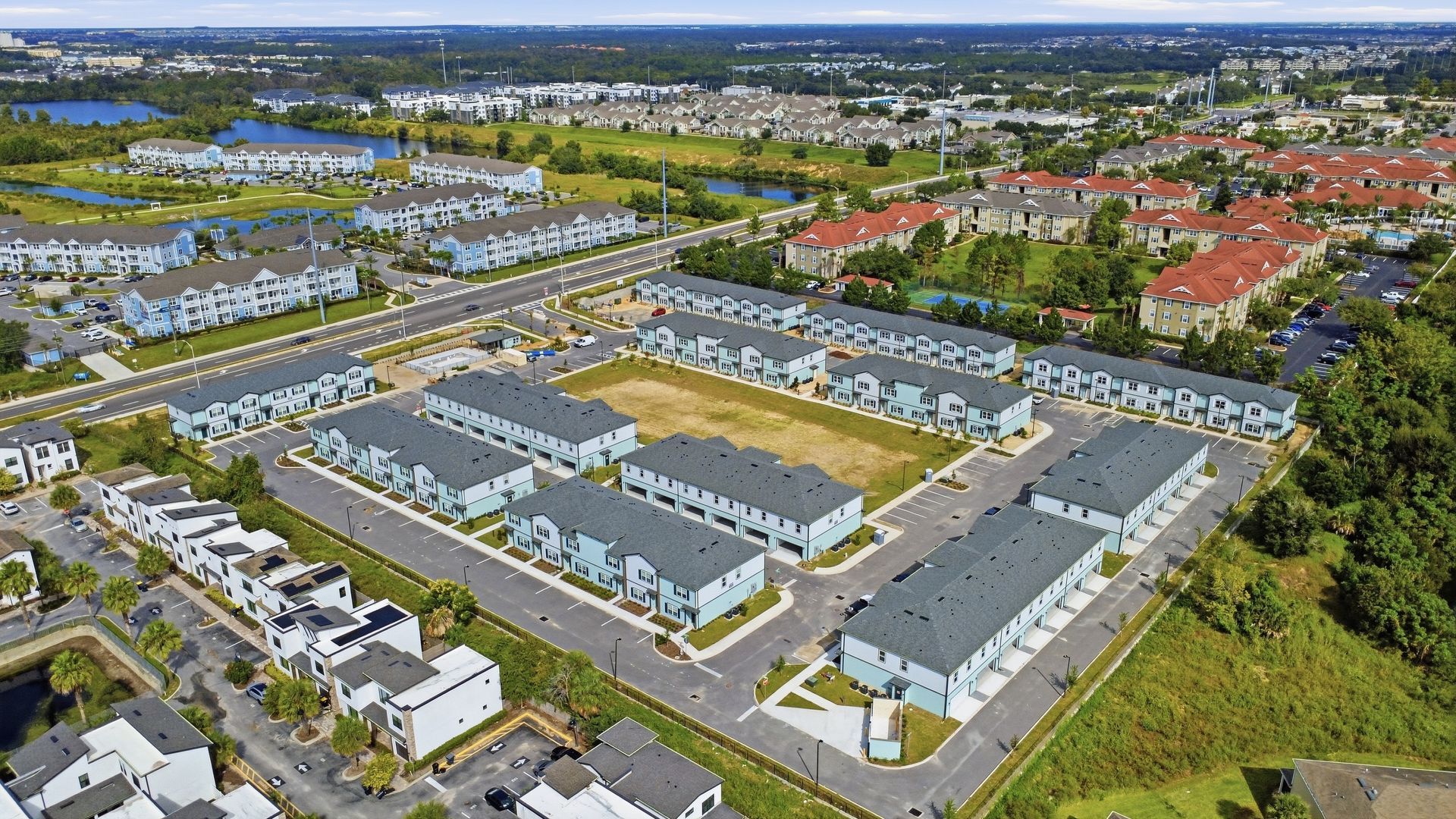 Aerial view of a residential neighborhood with rows of houses, streets, and green spaces.