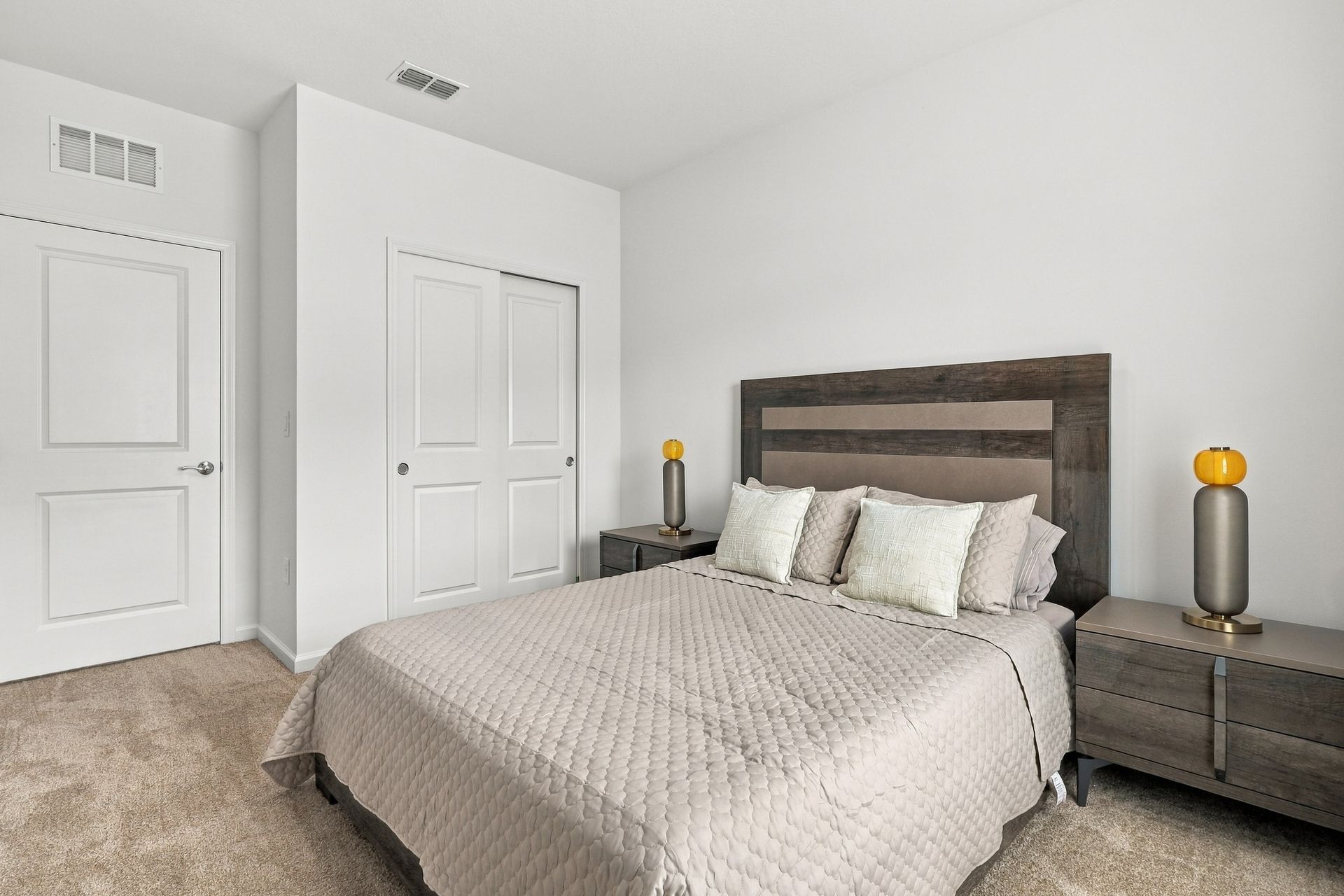 Bright bedroom with a gray bed, rustic wood headboard, and white double closet doors