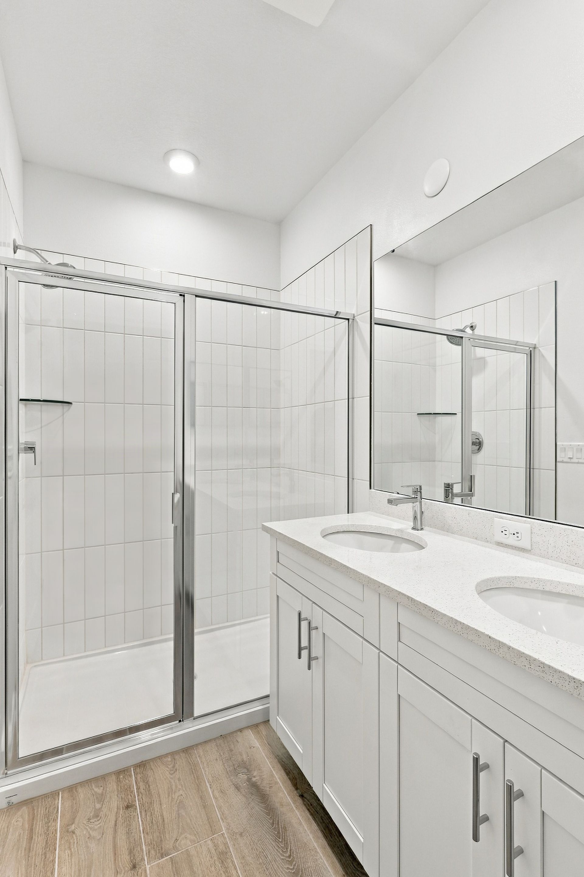 Bright modern bathroom with glass shower, white vanity, and marble countertop.