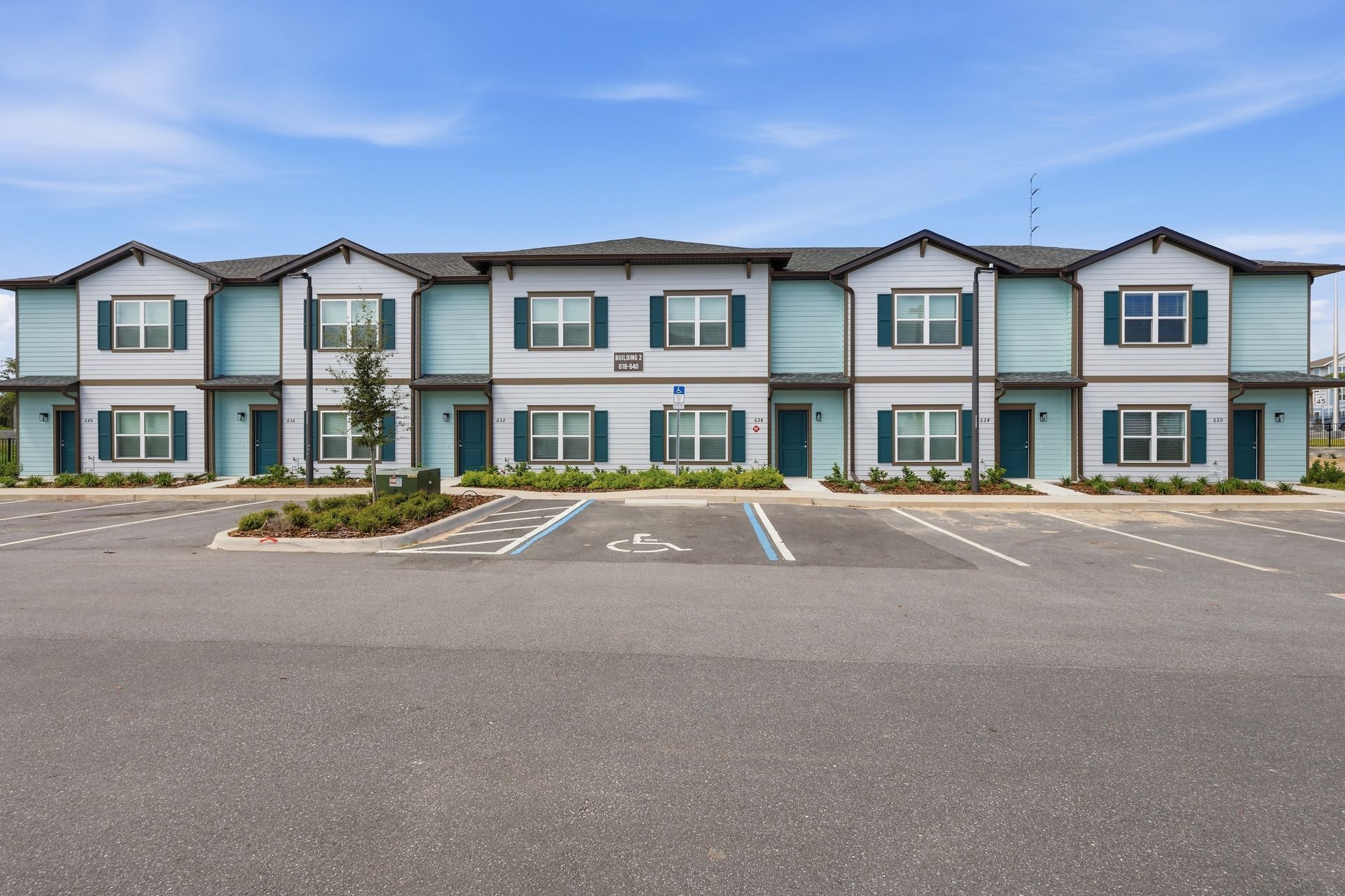 Row of modern townhouse apartments with blue-gray trim and empty parking spaces in front
