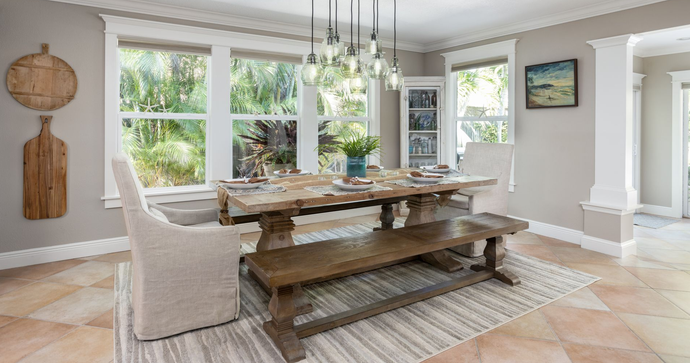Bright dining room with wooden table, bench seating, large windows, and soft neutral decor