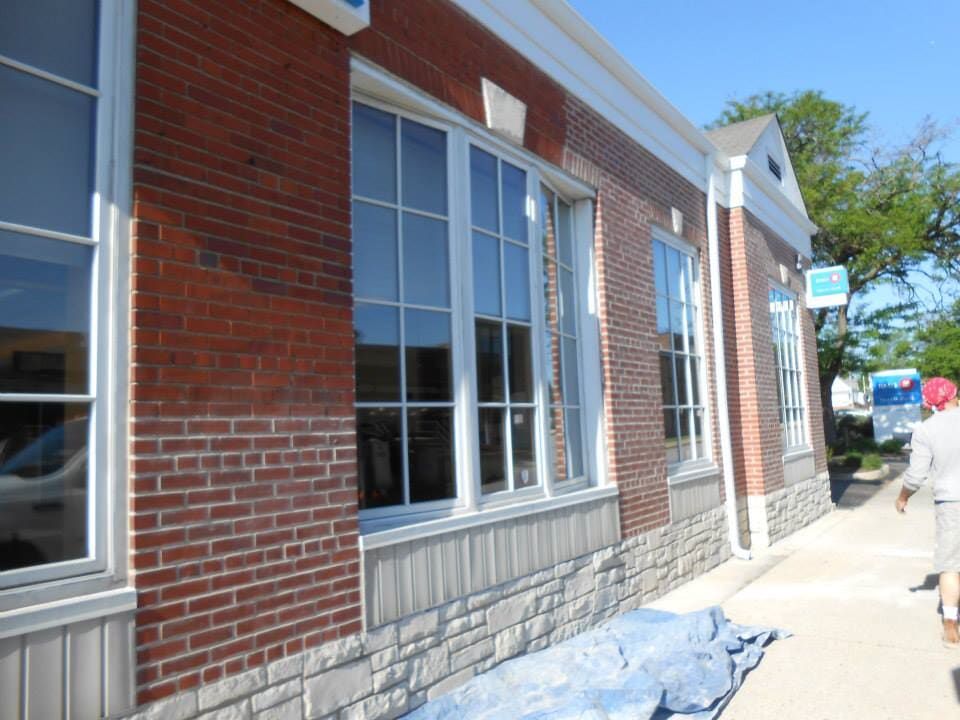 A brick building is being painted with white trim