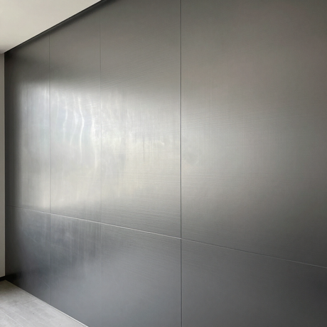 Parete rivestita con pannelli grigi e giunzione diagonale in uno spazio interno minimalista.