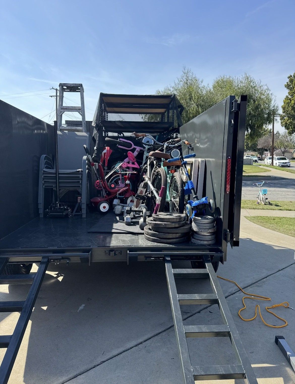 A truck bed filled with scrap metal and various bicycles on a sunny day.