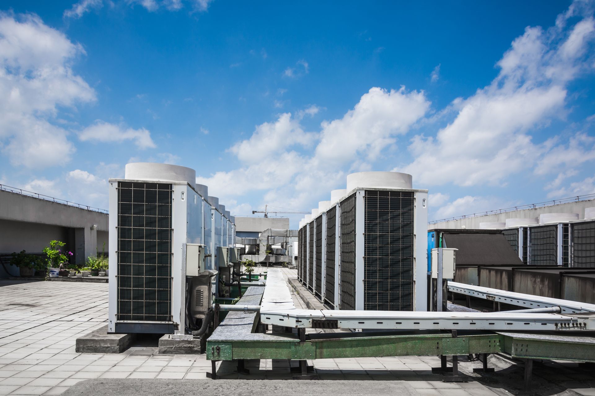 Rooftop HVAC units and vents under a blue sky with clouds