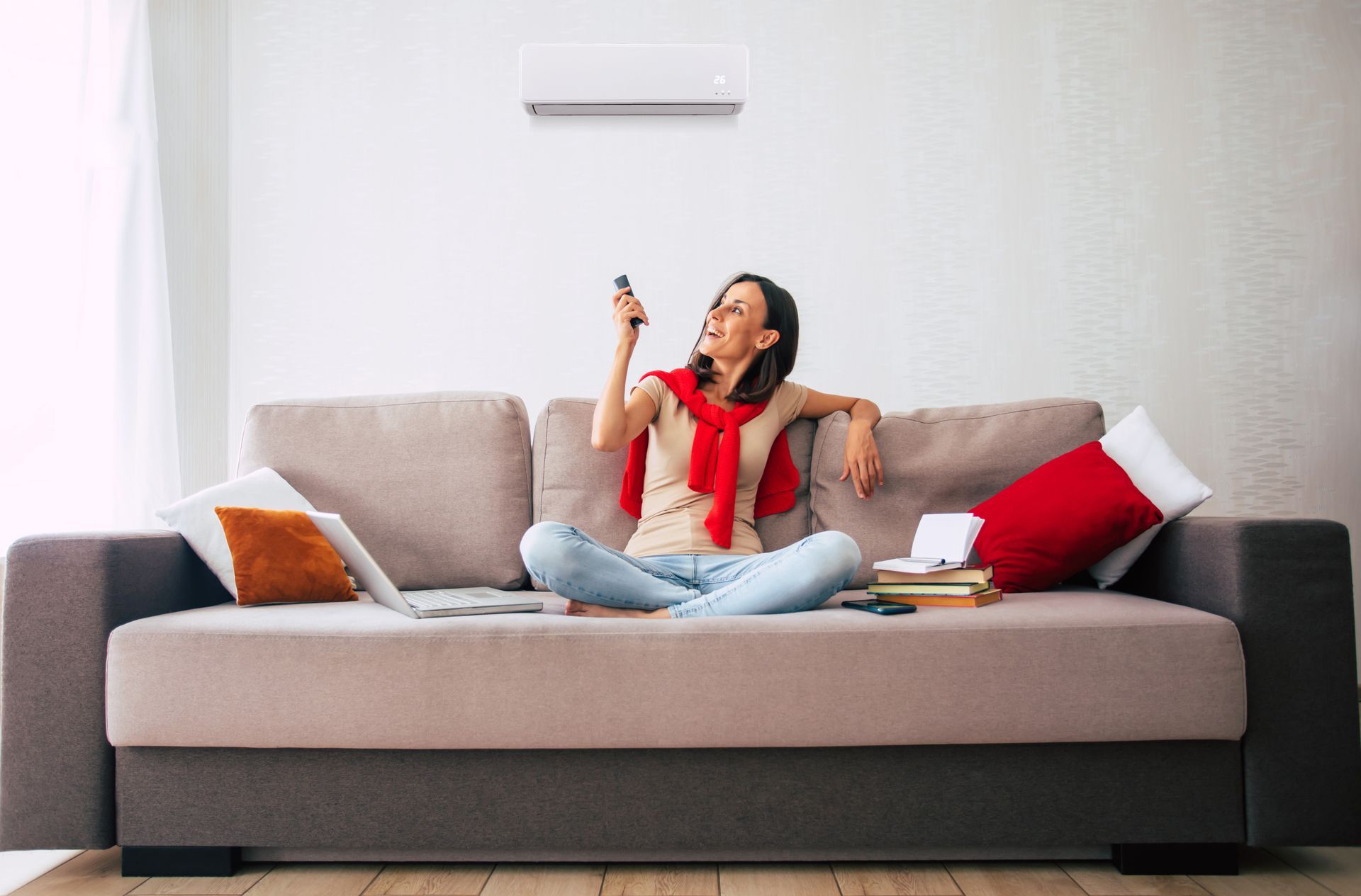 Woman lounging on a sofa, smiling and holding a remote in a bright living room