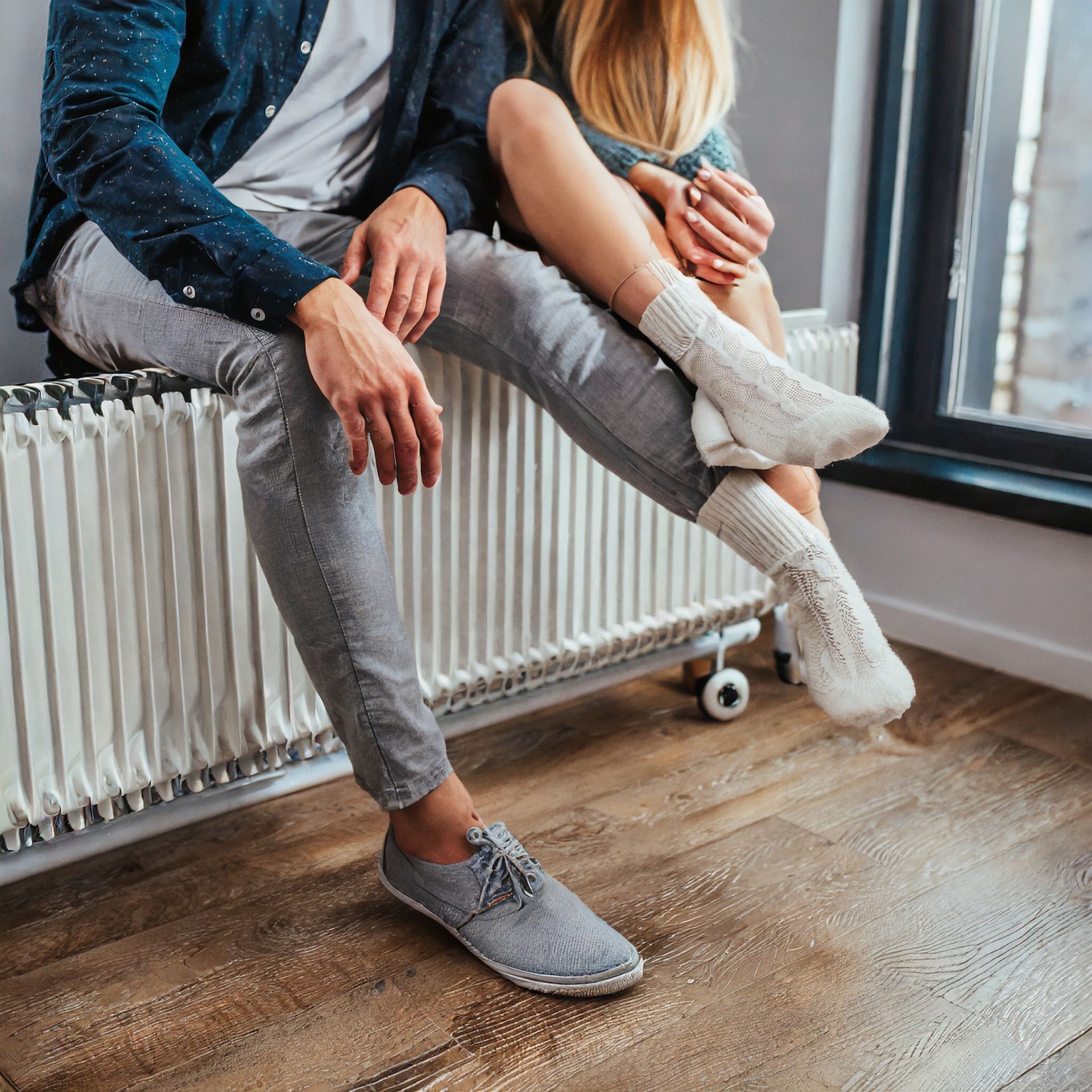 A man and a woman are sitting on a radiator with their legs crossed