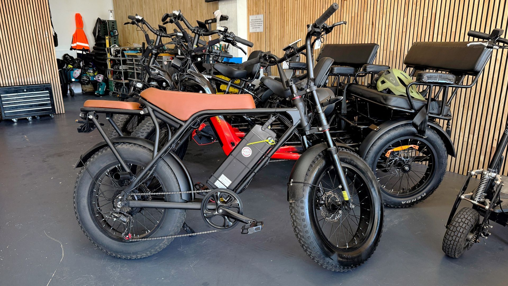 A black electric bike with brown seat and a few more in a shop setting — E-Go-Try-Bikes in Nelson Bay, NSW