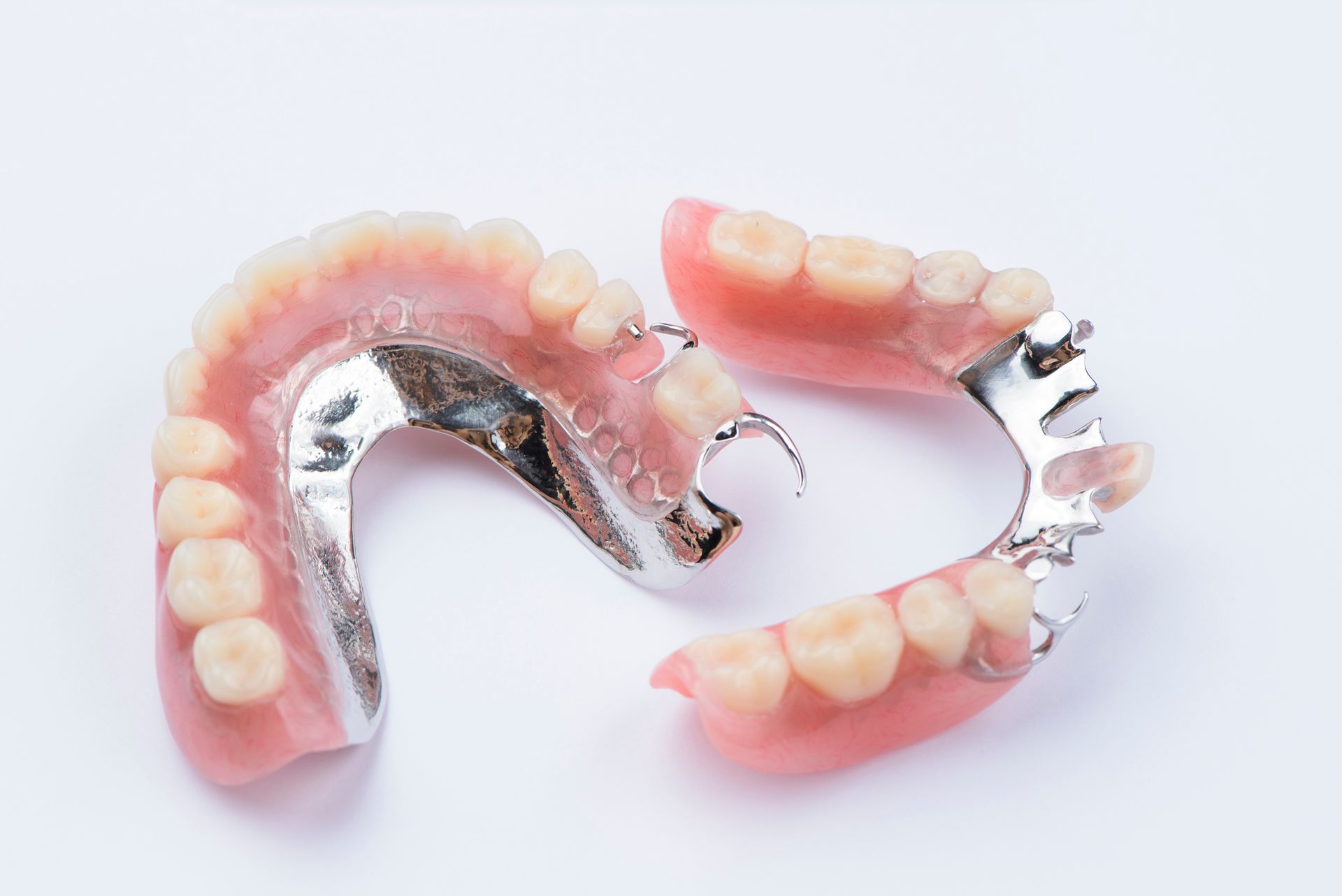 Partial dentures with pink gums and beige teeth on a white background.
