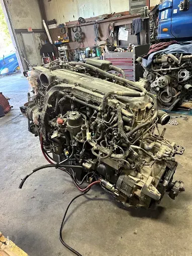 Red truck engine on a surface, with various mechanical parts and tubes attached.