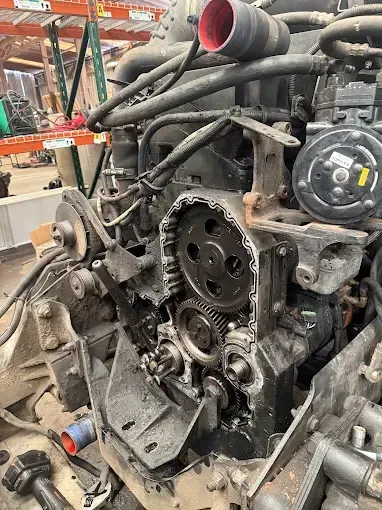Engine of a large vehicle, showing mechanical parts and wiring in a repair shop.