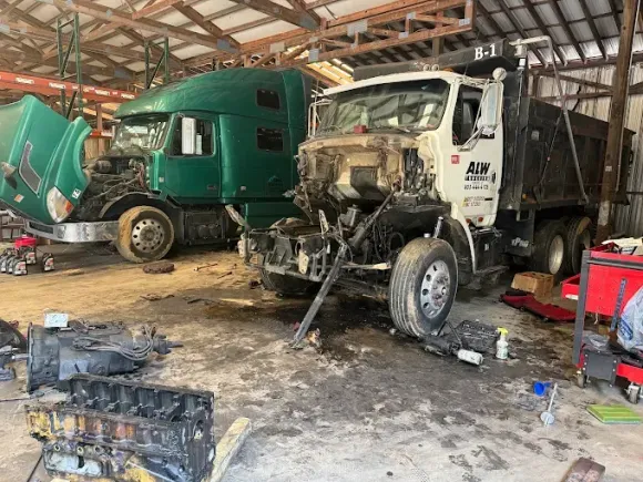 Red truck with hydraulic lift, various components exposed, outdoors.