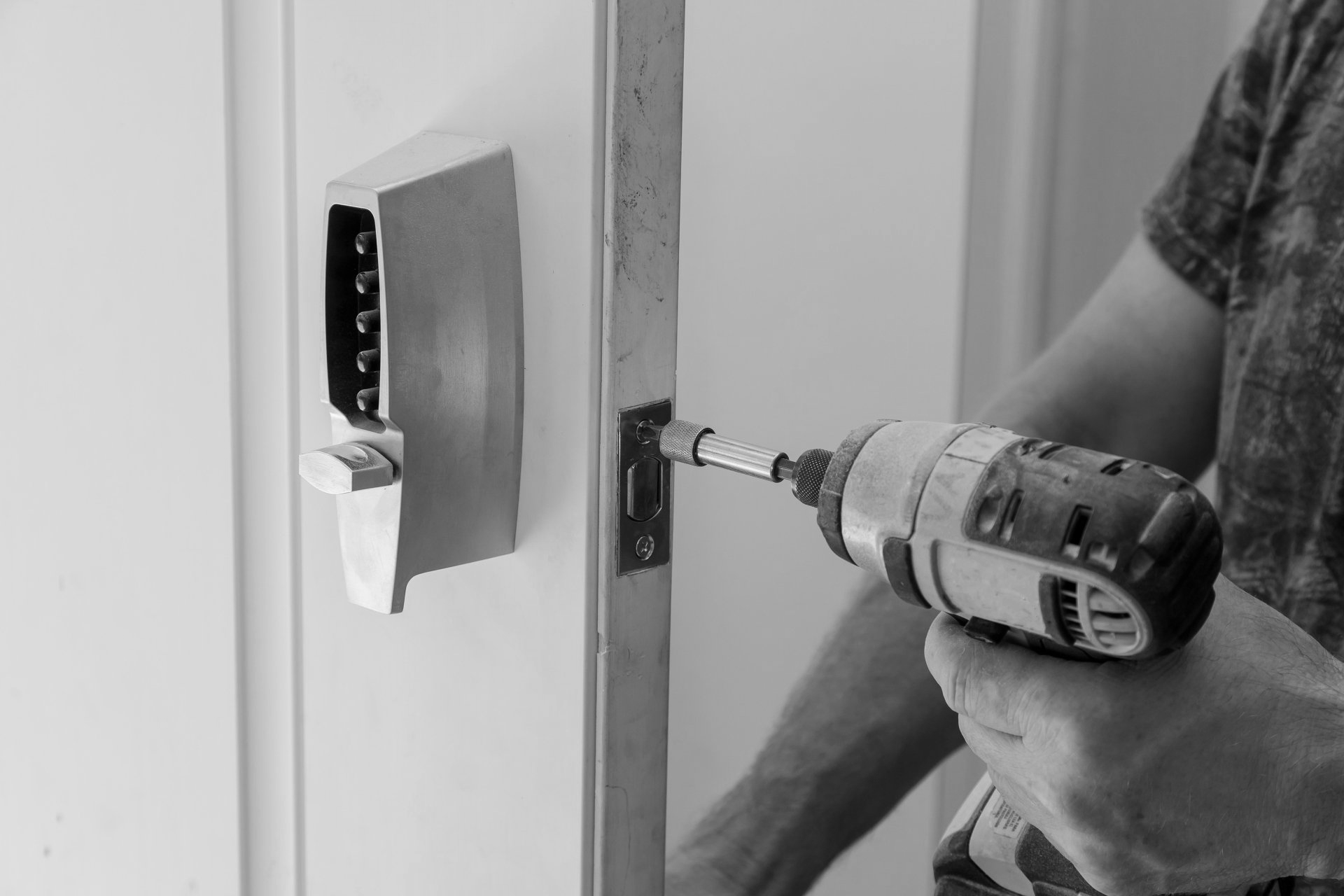 Un homme utilise une perceuse pour installer une serrure de porte.