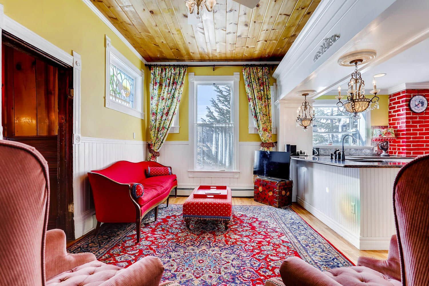 A living room with a red couch , chairs and a rug.