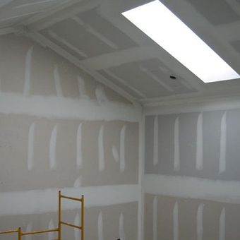A room with a vaulted ceiling and a ladder in the corner