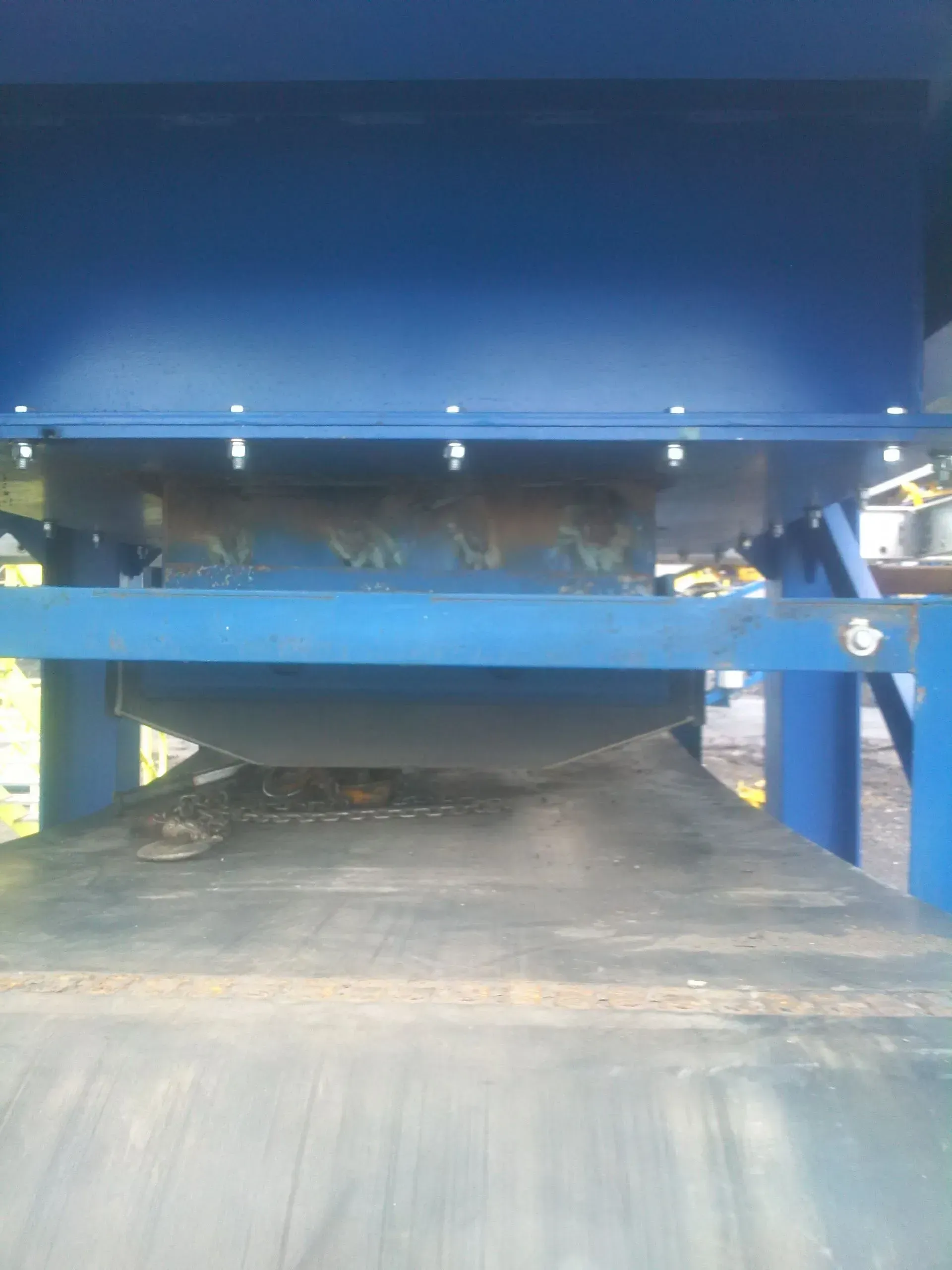 A blue machine is sitting on top of a conveyor belt.