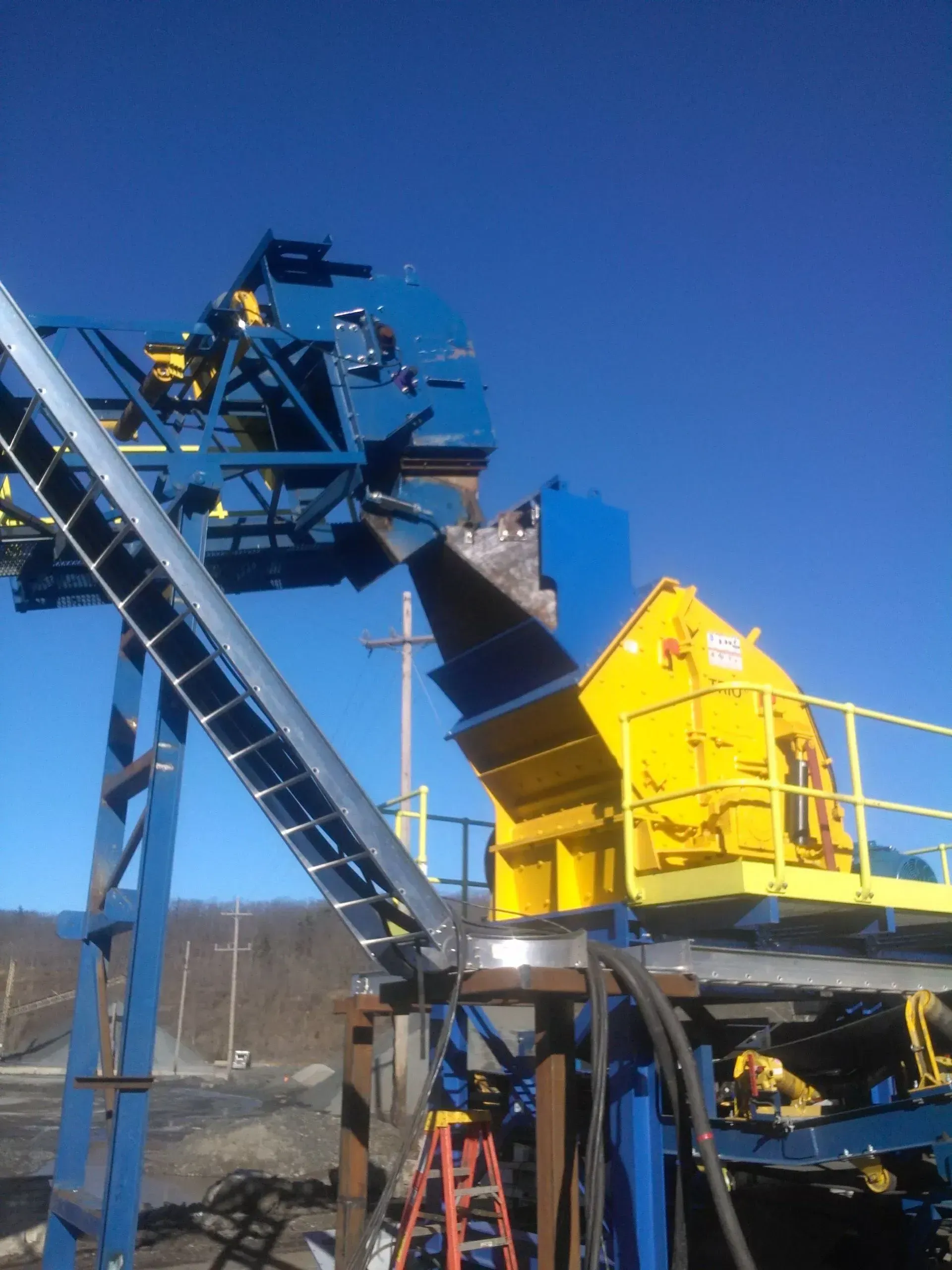 A blue and yellow machine with a ladder in front of it.