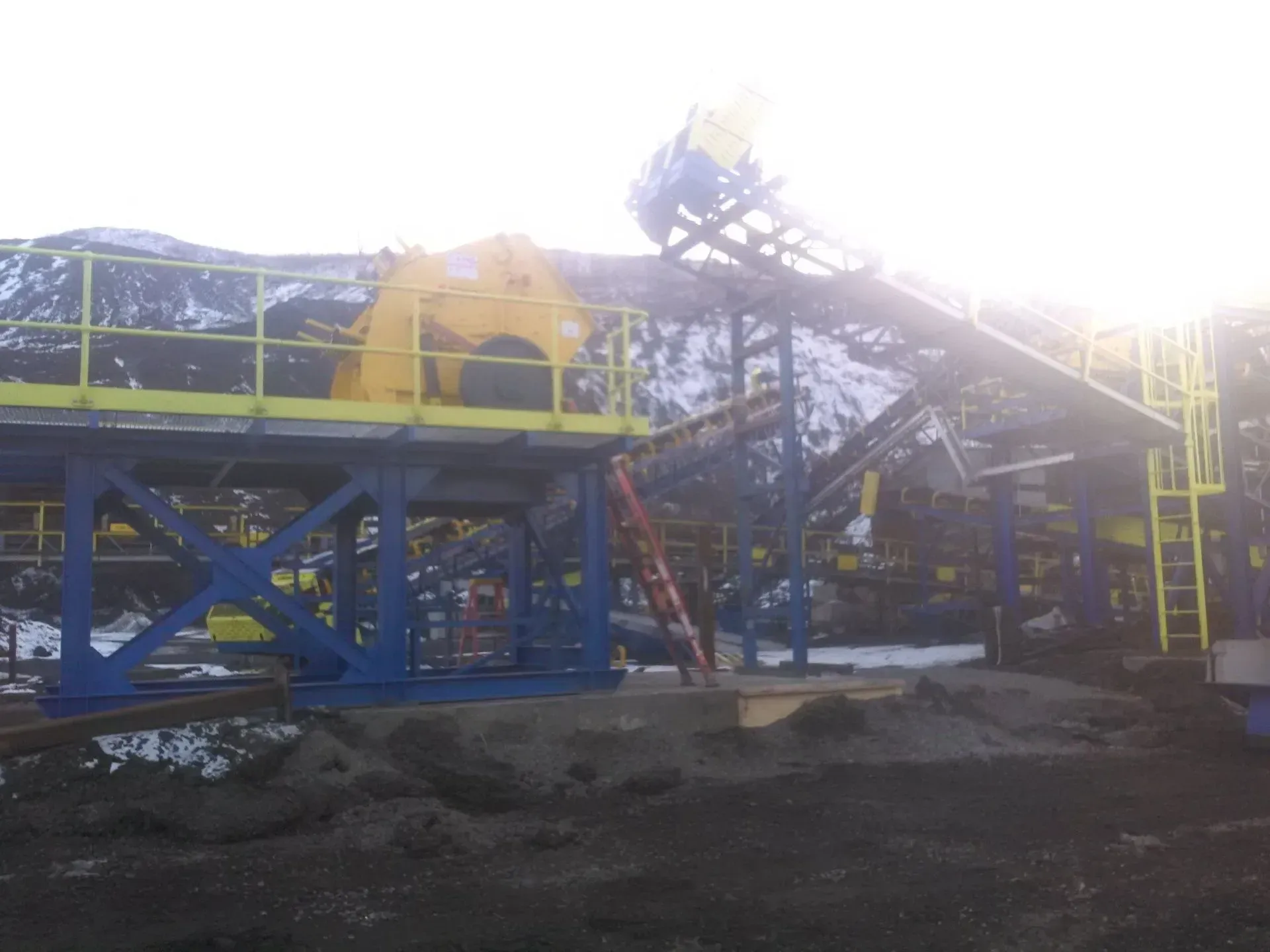 A large blue and yellow machine is sitting on top of a dirt field.