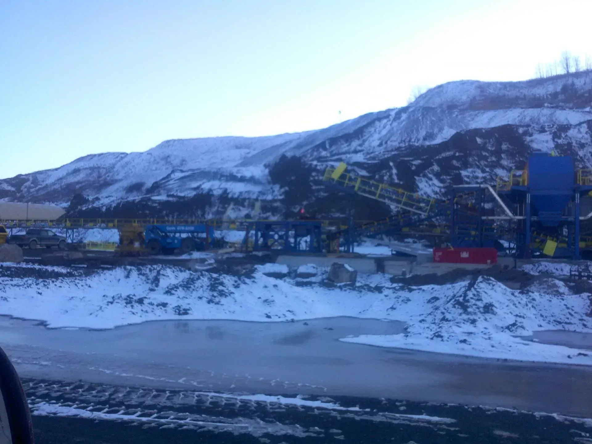 A view of a snowy mountain from a car window.