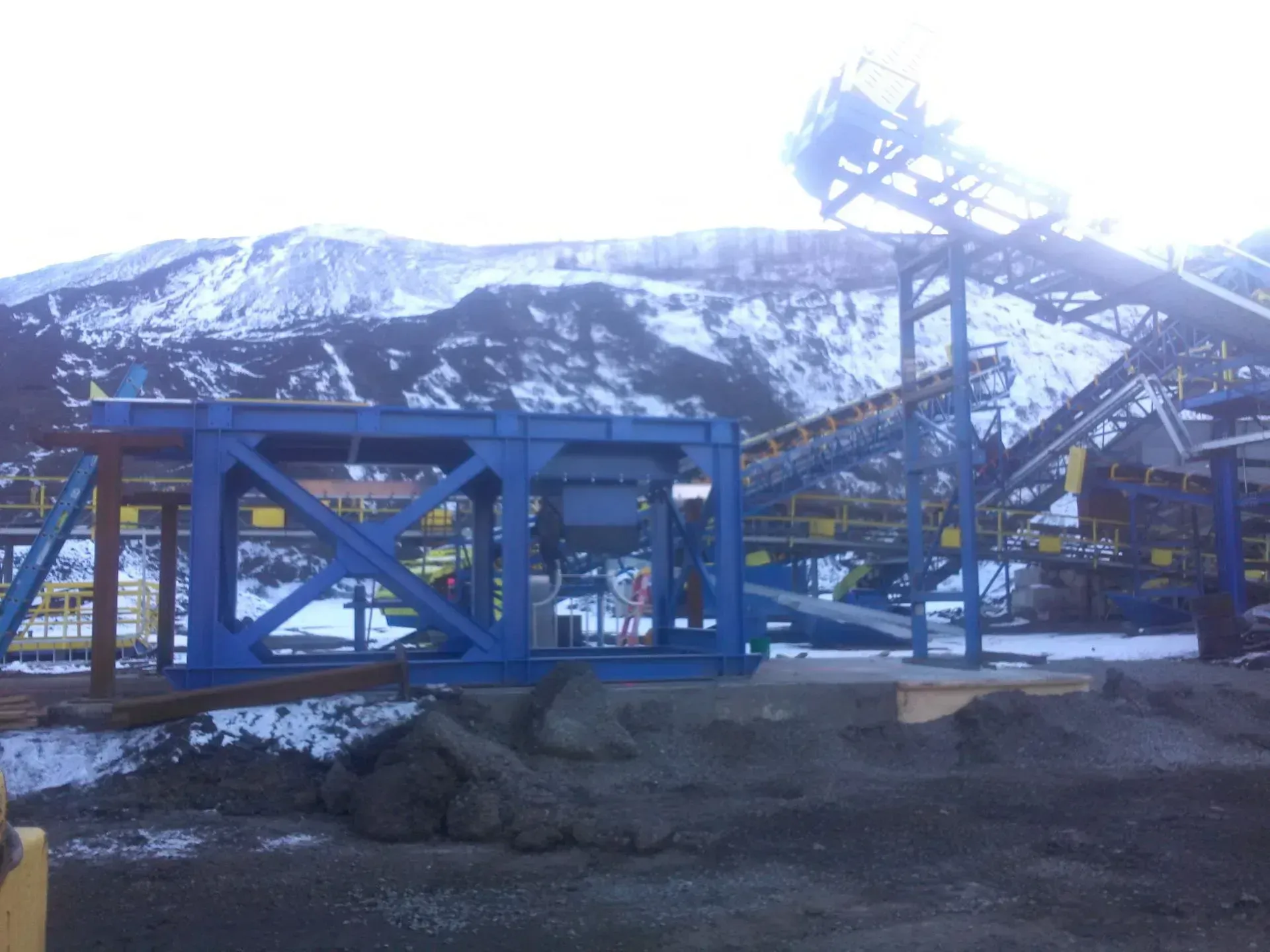 A large blue structure is sitting in front of a snowy mountain.