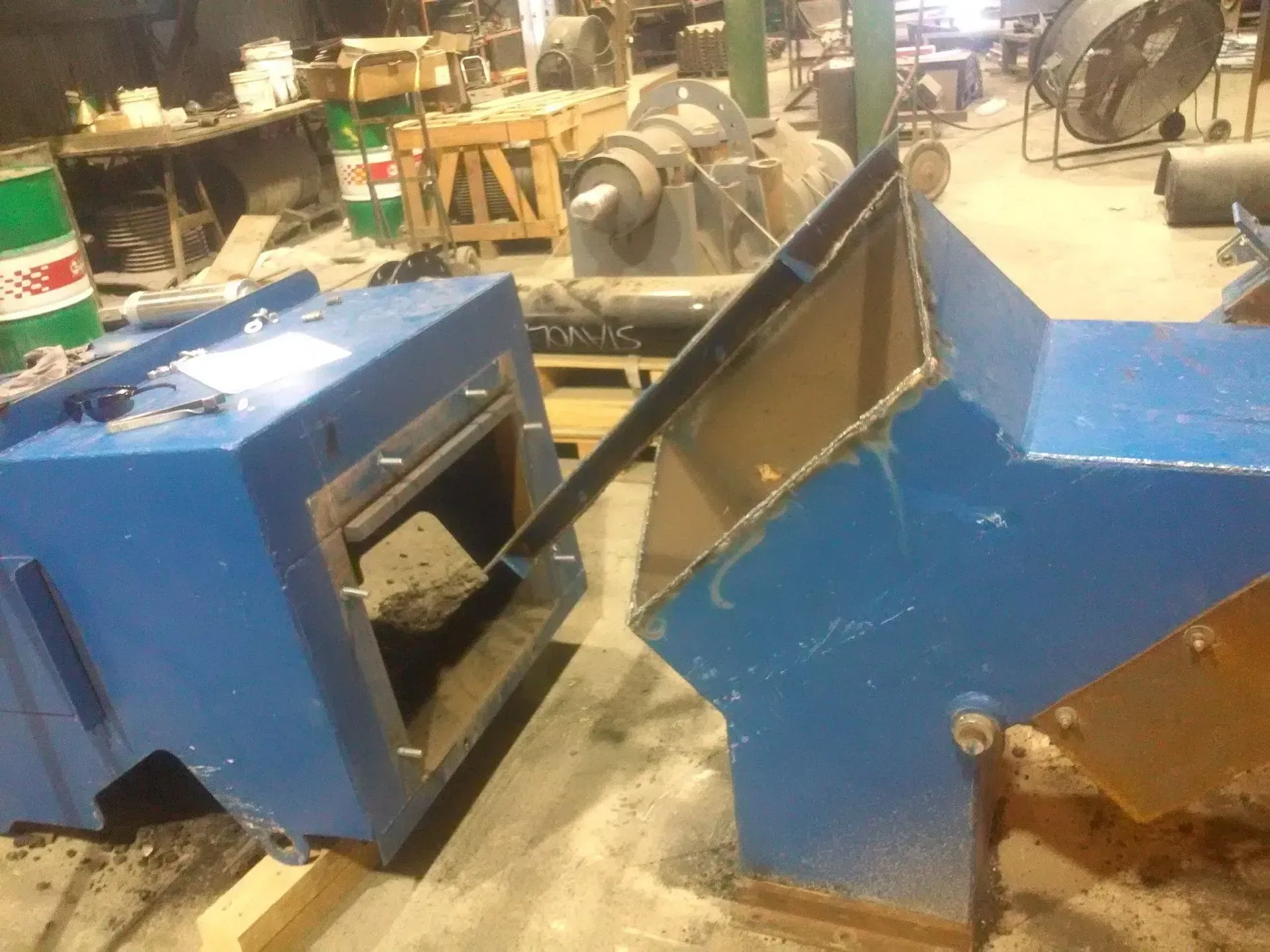 Two blue boxes are sitting on the ground in a warehouse.