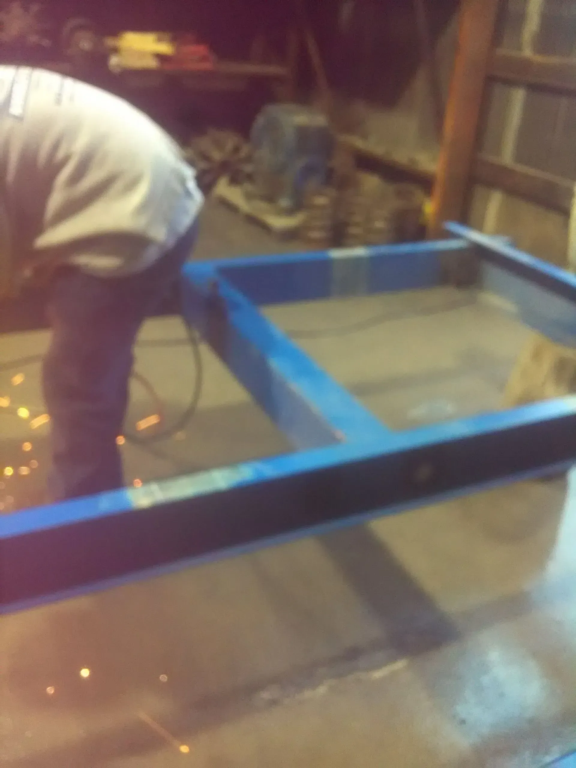 A man in a white shirt is working on a blue frame.