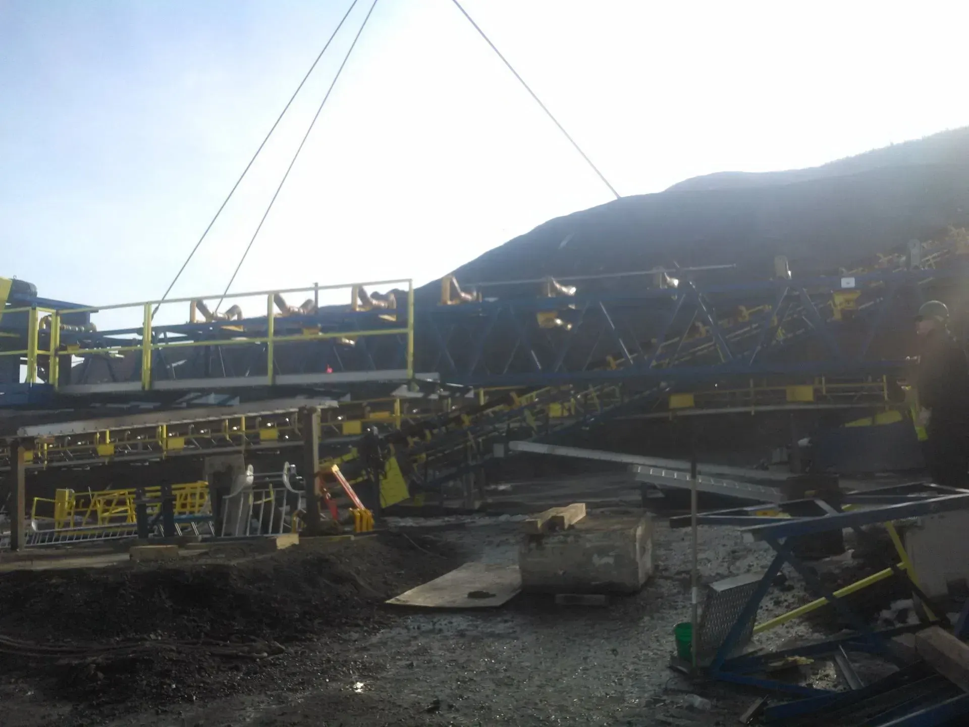 A large conveyor belt is being lifted by a crane.