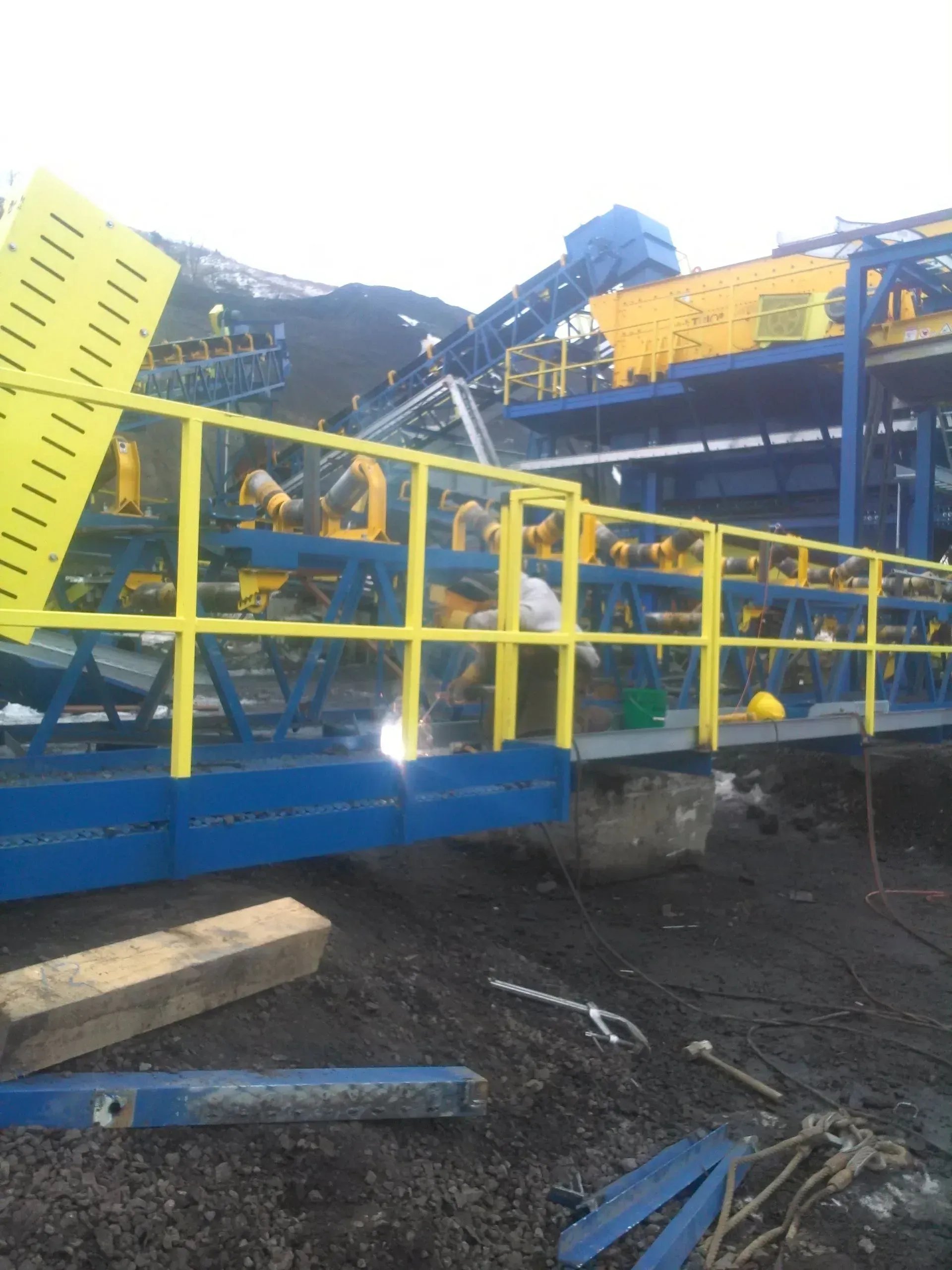 A yellow railing surrounds a blue and yellow conveyor belt.