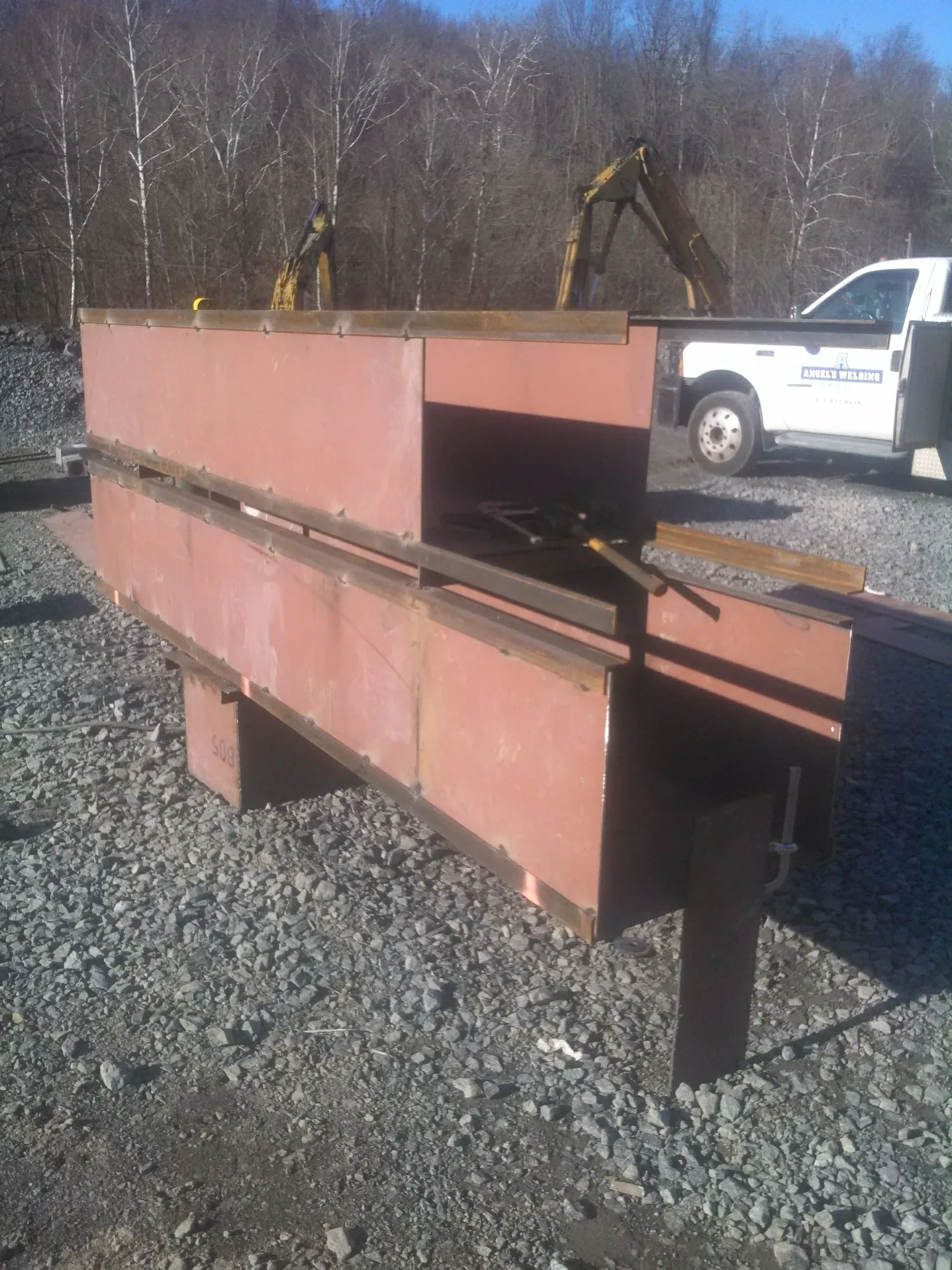 A white truck is parked next to a pile of metal pieces.