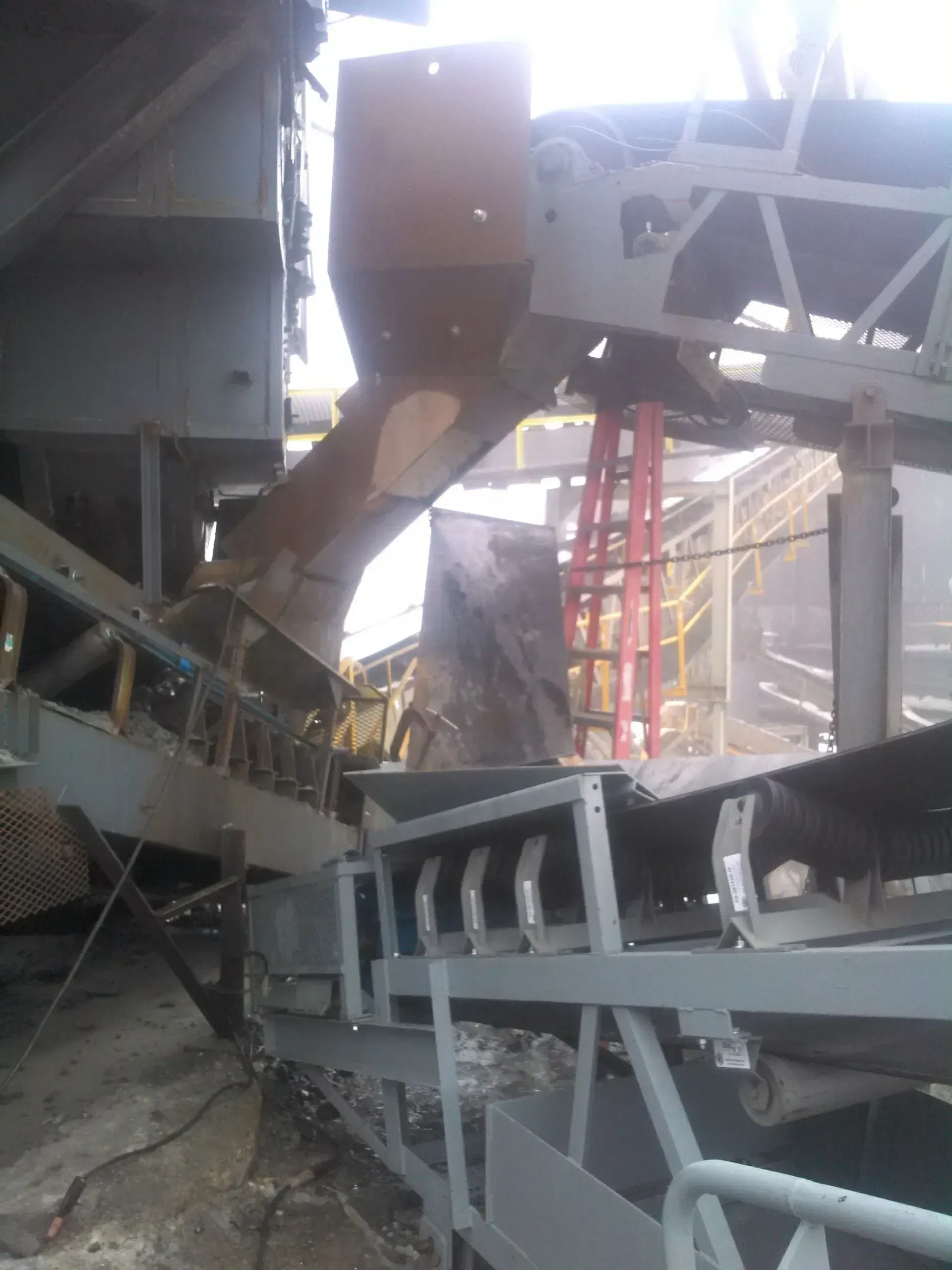 A conveyor belt in a factory with a ladder in the background.