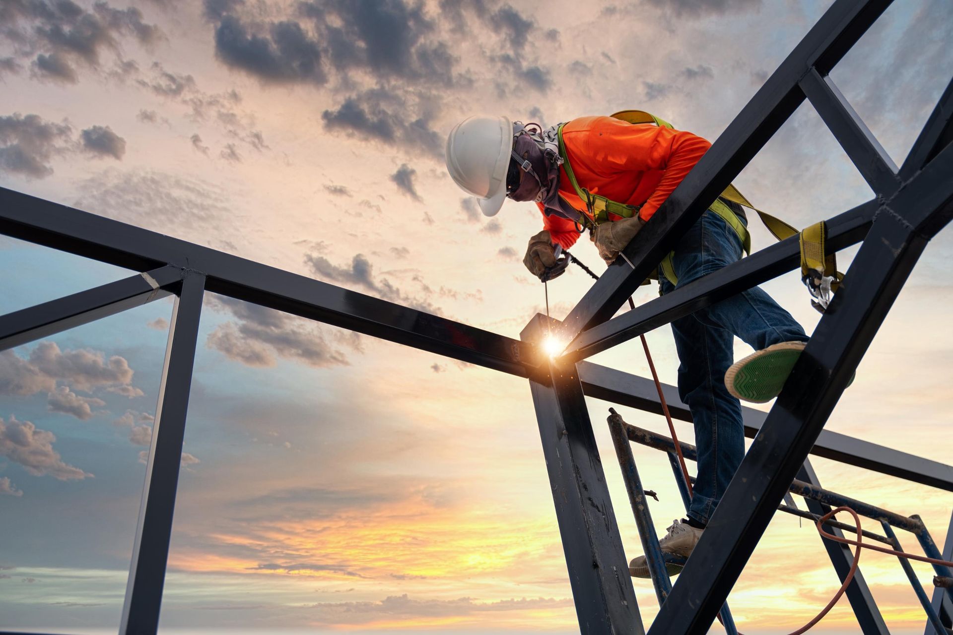 A construction worker is welding a metal structure on a scaffolding.