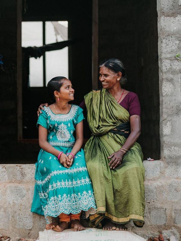 Girl sits with a woman in her life as part of Restoring Hope's family-based model of care for orphans & vulnerable children