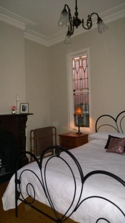 A bedroom with a wrought iron bed and a fireplace
