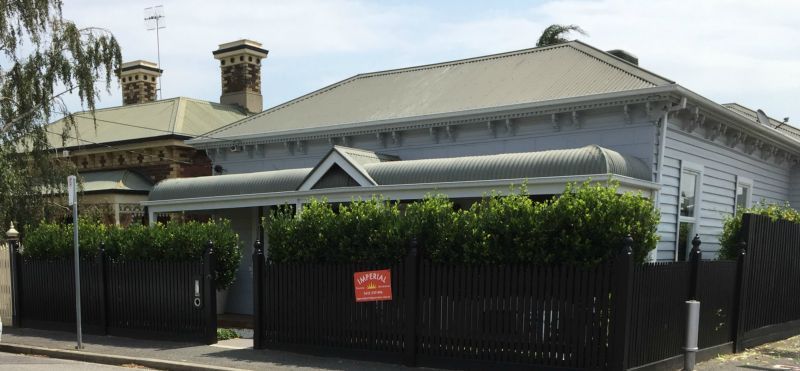 A white house with a black fence and a for sale sign