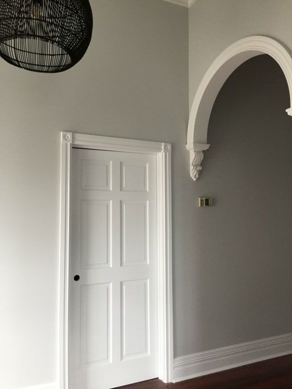 An empty room with a white door and a black chandelier hanging from the ceiling.