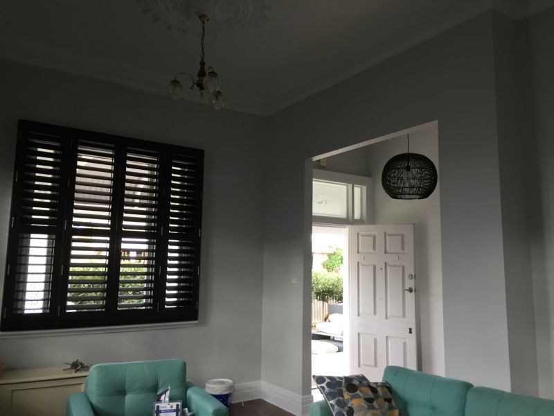 A living room with a blue couch and black shutters
