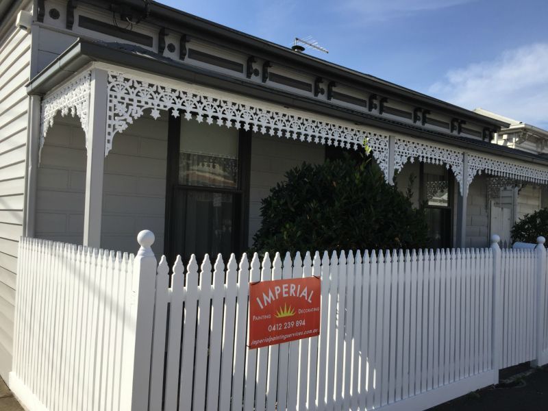 A white picket fence with a sign that says imperial